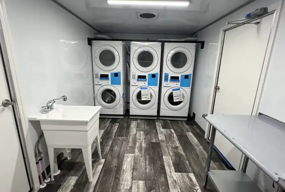 Modern commercial laundry room with stacked washers and dryers for rent at Montondo Trailers.