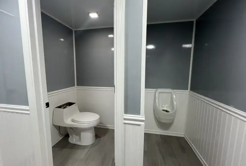 Portable bathroom trailer with modern fixtures and privacy partitions for events or construction sites.